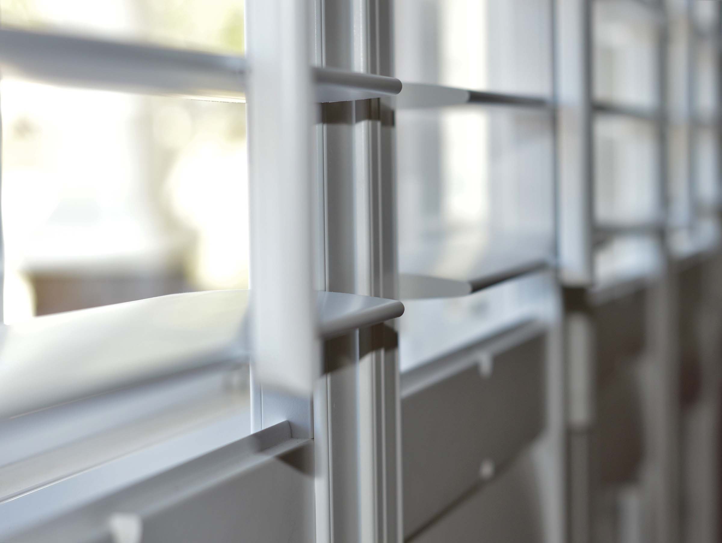 An extreme close-up, shallow-depth-of-field view of white plantation shutters