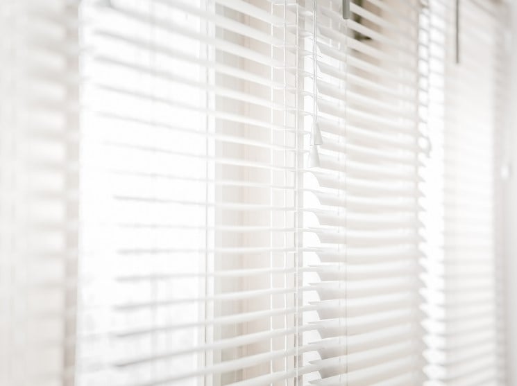 Blog » A bright, overexposed close-up shot of white horizontal Venetian blinds