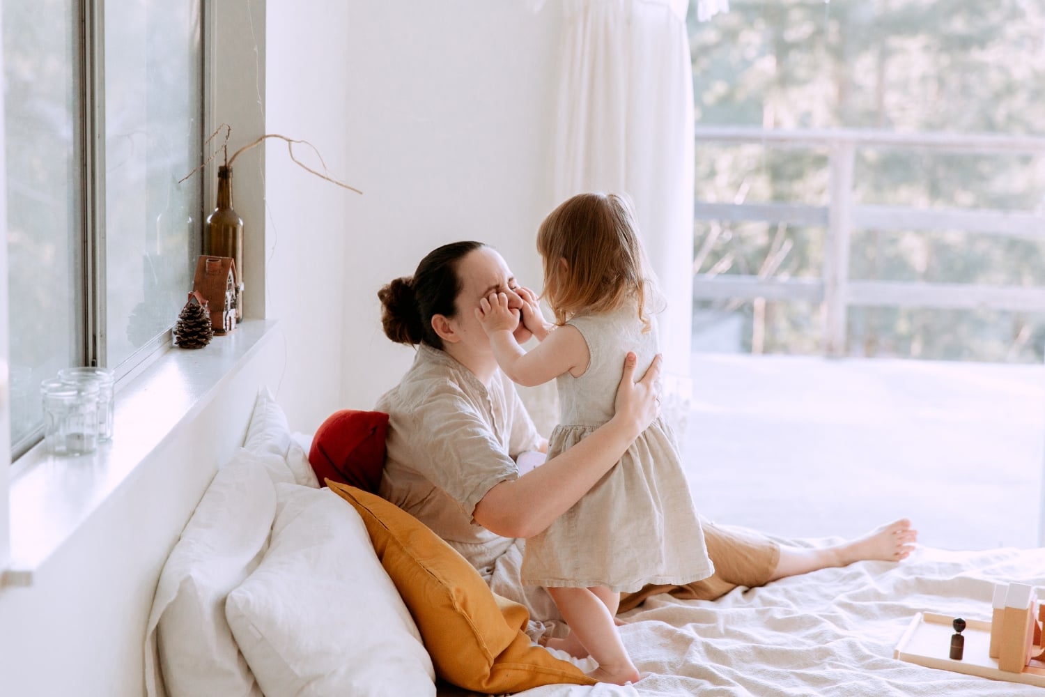 Blog » A mother and young daughter sharing a playful moment on a bed